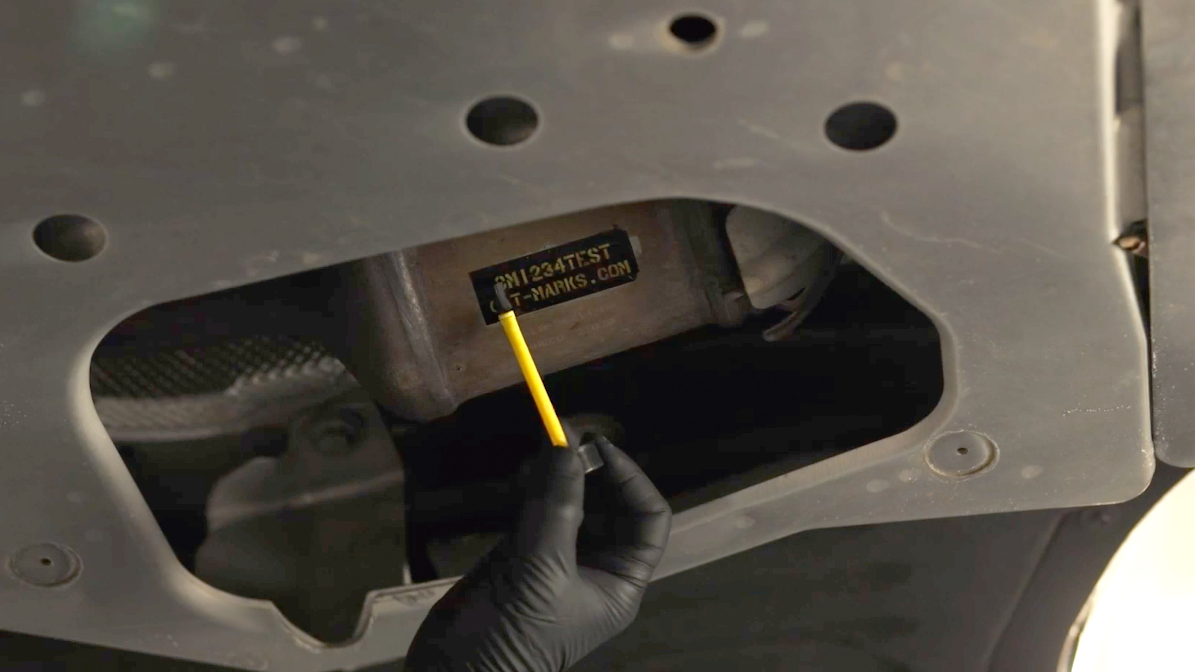 Applicator brush next to a stencil attached to a catalytic converter.